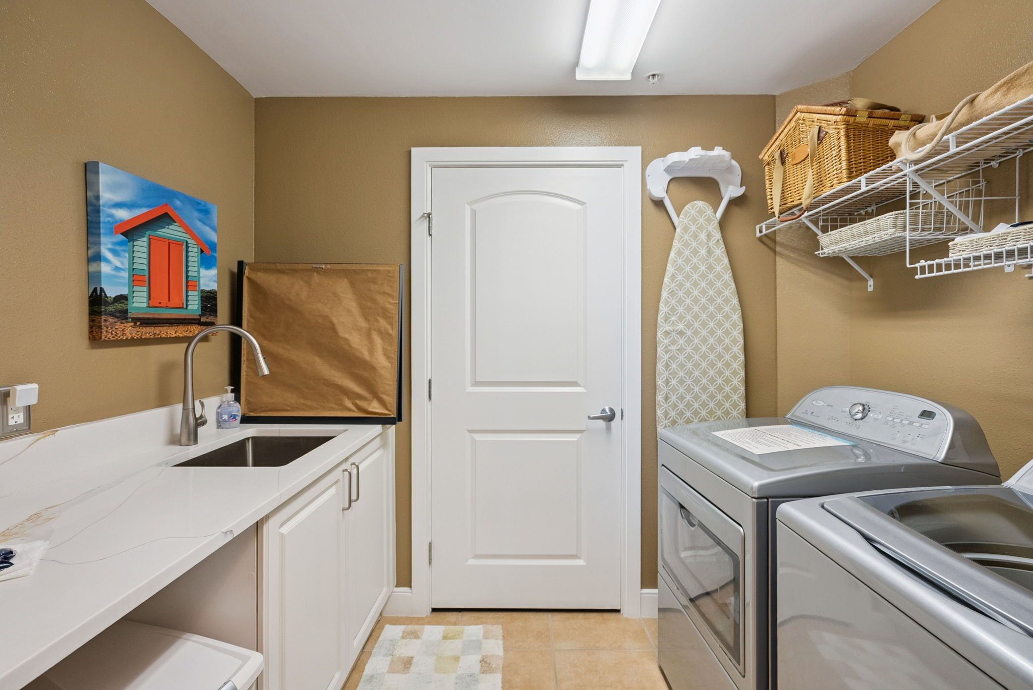 A compact laundry room with a washing machine, dryer, and a small sink.