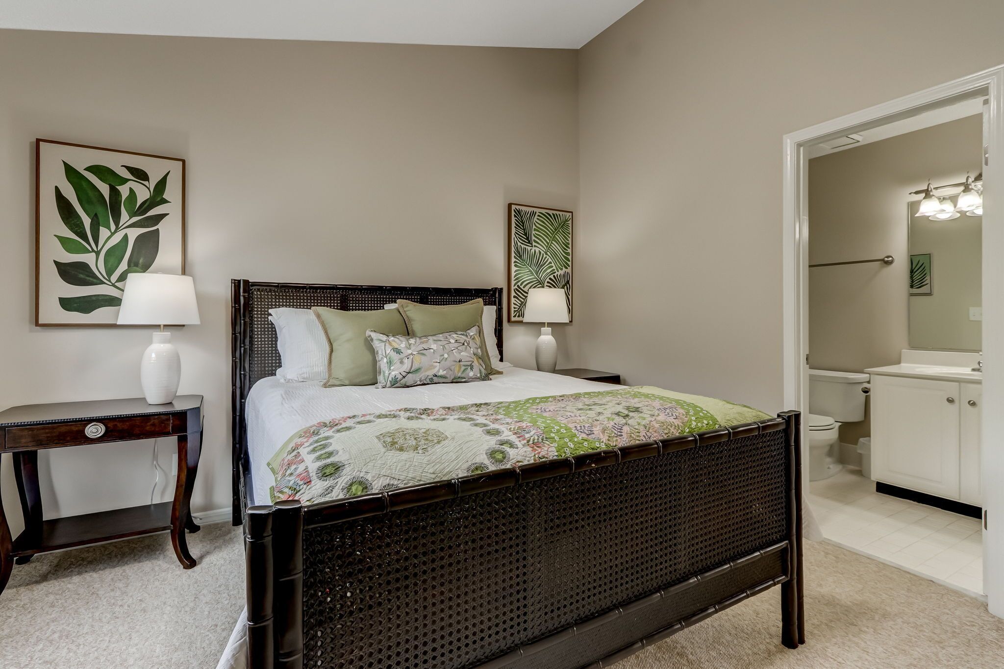A bedroom with a dark wooden bed, two bedside tables with lamps, and a large mirror above the door.