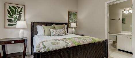 A bedroom with a dark wooden bed, two bedside tables with lamps, and a large mirror above the door.