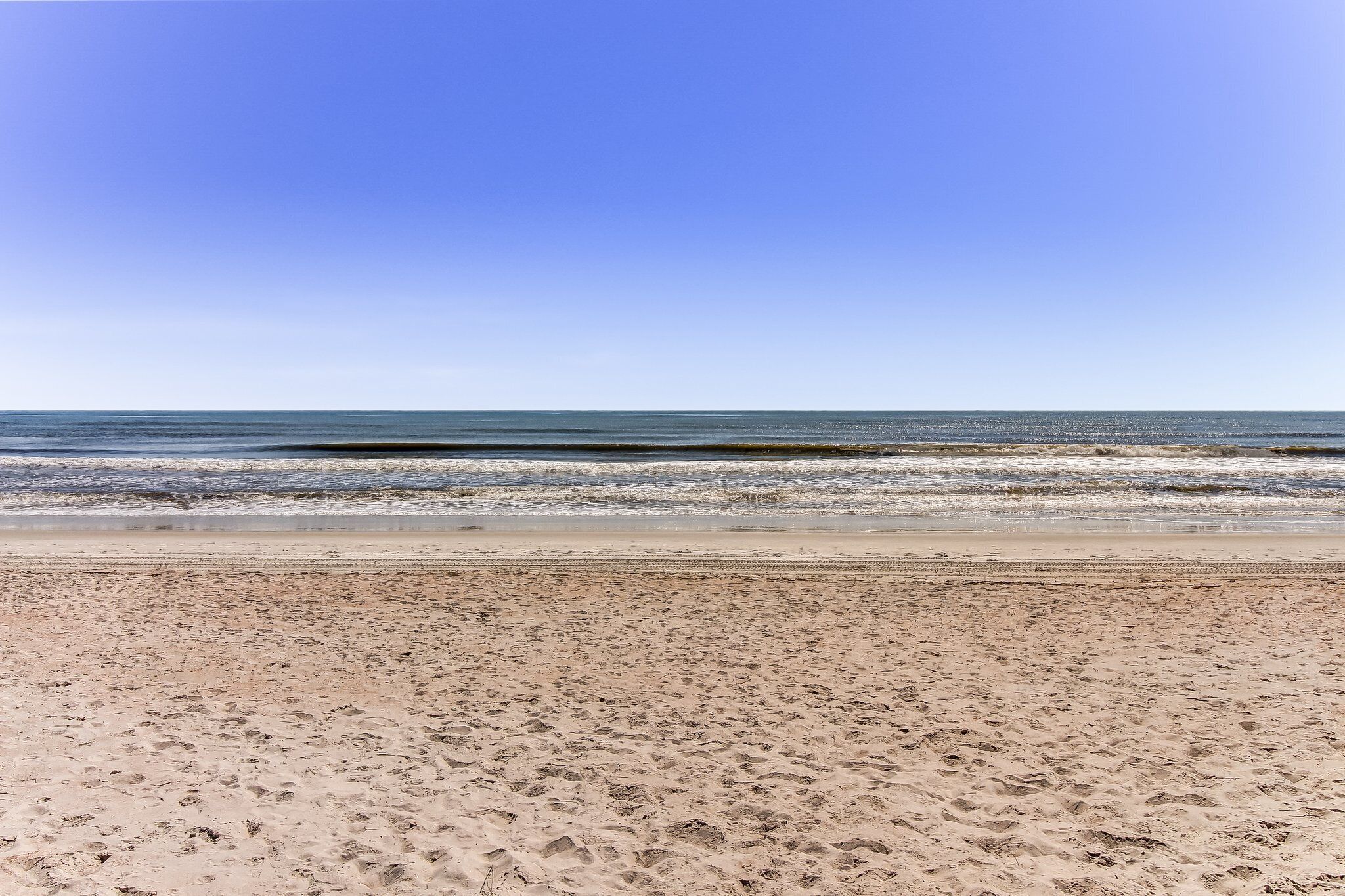 Ein Strand mit blauem Himmel und ruhiger See.