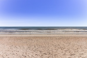 En strand med klart himmel og roligt hav.