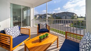 Ein Balkon mit einem Holztisch, zwei blauen Sitzgelegenheiten und Blick auf Nachbarhäuser.