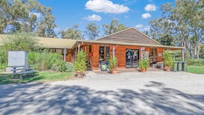 A rustic building with a wooden facade, a covered porch, and a signboard. - Torrumbarry Weir Holiday Park (Patho)