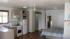A compact room with a kitchenette, a bed, and a ceiling fan. - Torrumbarry Weir Holiday Park (Patho)