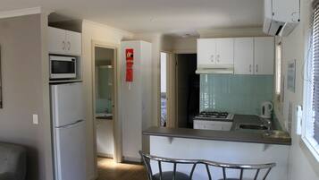 A compact kitchen with white cabinets, a microwave, and a gas stove.