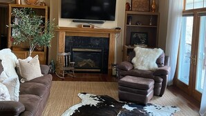 A living room with a fireplace, a mounted deer head, a television, and a cowhide rug.