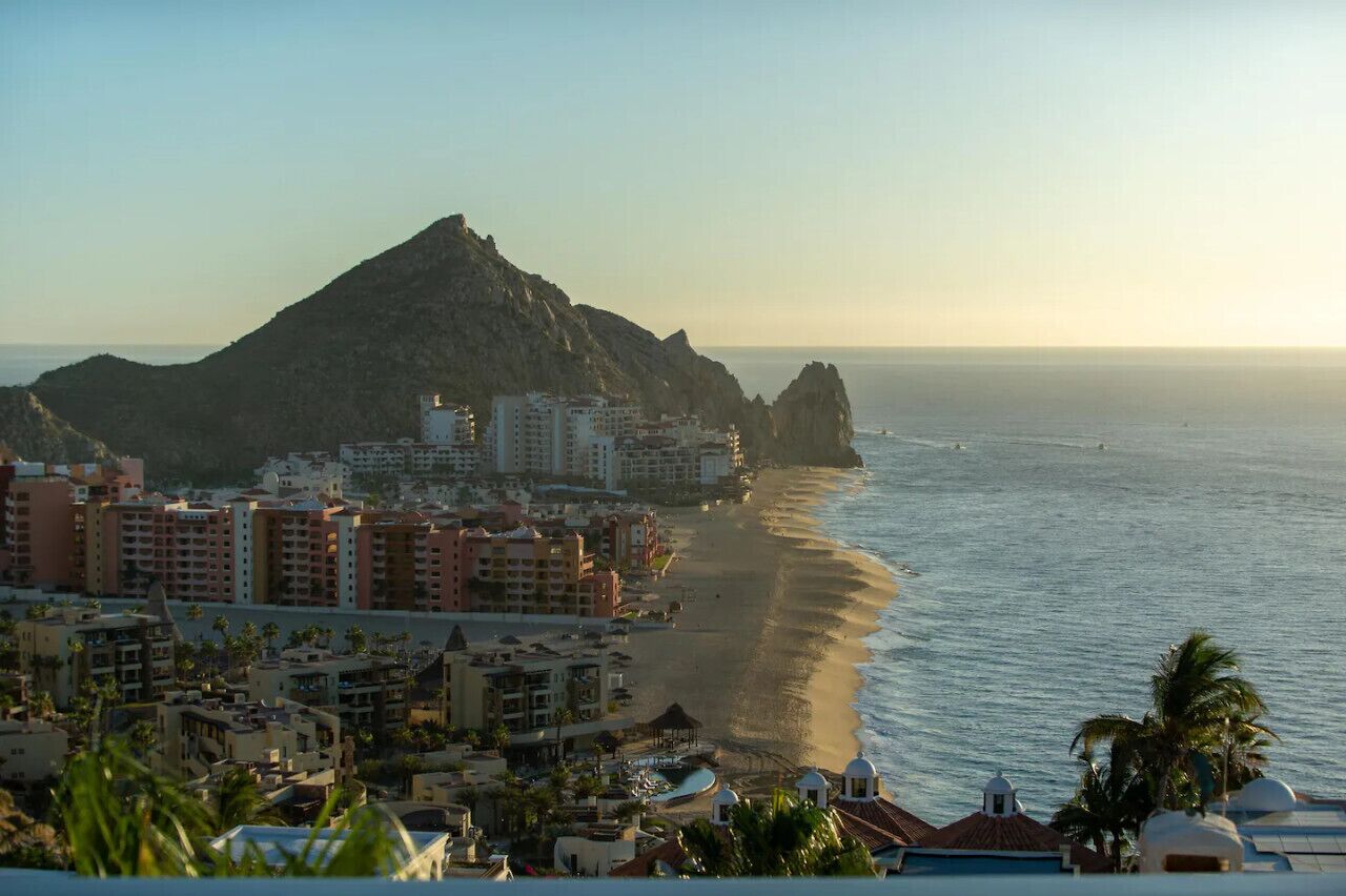 A coastal cityscape with a prominent mountain, beachfront hotels, and clear skies.