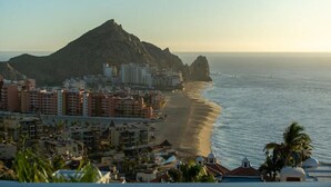 Un paysage urbain côtier avec une montagne imposante en arrière-plan, des hôtels situés en bord de mer et un ciel dégag é.