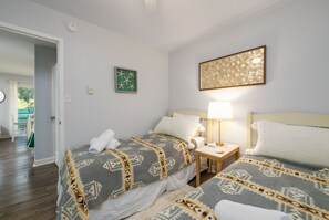 A hotel room with two beds, a nightstand, a lamp, and a framed picture on the wall.