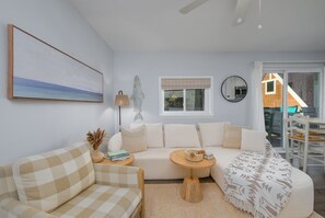 A modern living room with a sofa, a coffee table, and a painting on the wall.