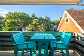 An outdoor seating area with a table and chairs, a wooden fence, and a house in the background.