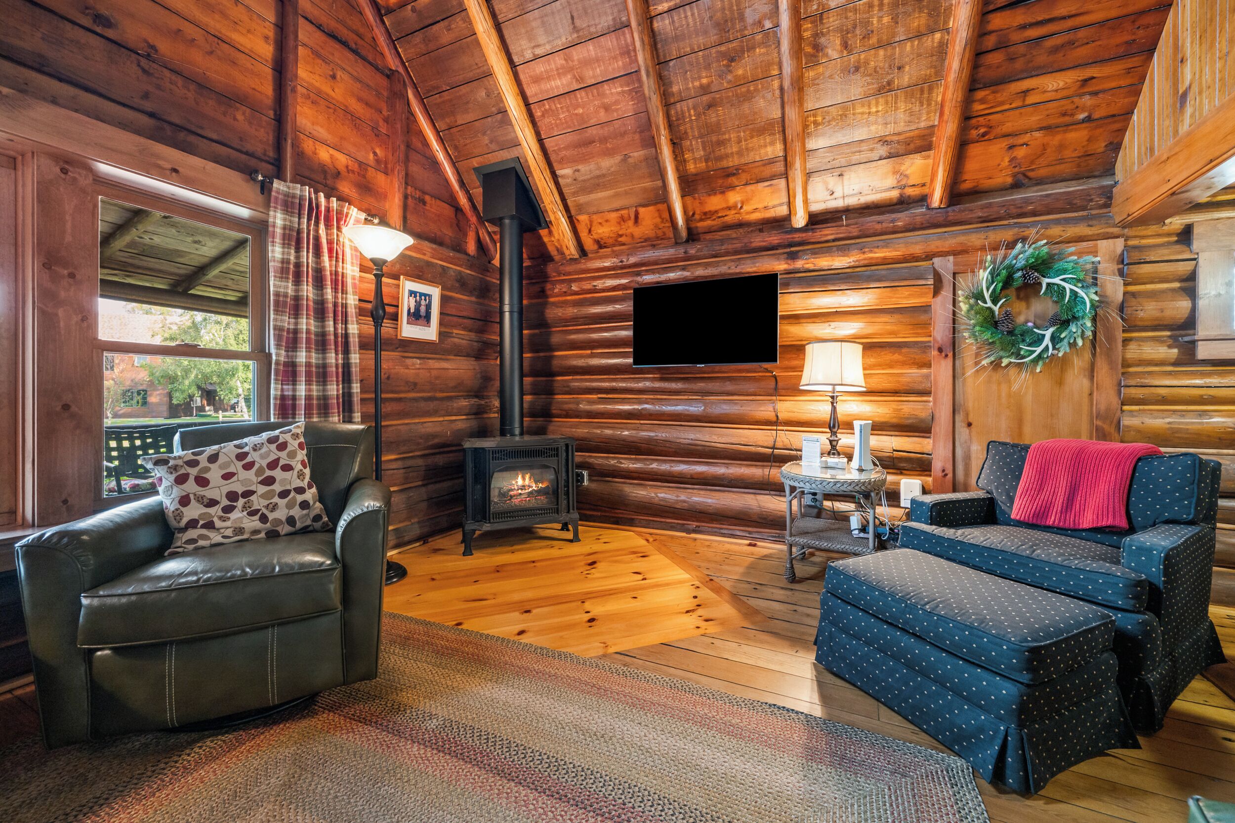 Een knus interieur van een chalet, met een open haard, lederen meubels en een aan de muur bevestigde televisie.
