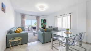 Ein modernes Wohnzimmer mit einem Glastisch, grauen Sofas und Blick ins Freie.