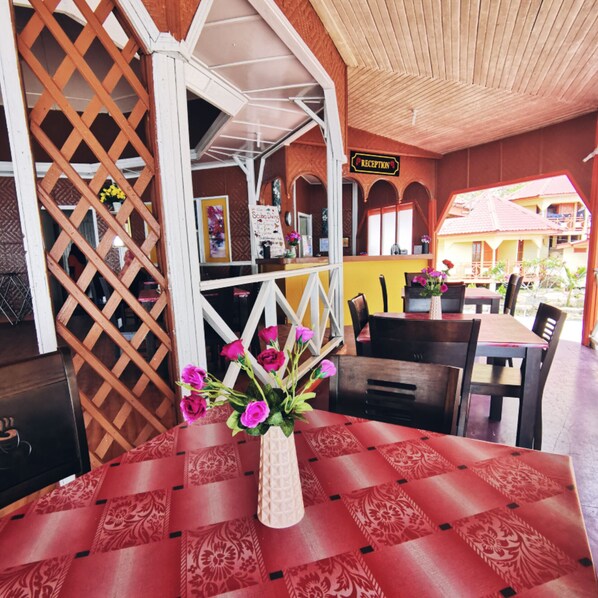 Uma área de recepção com balcão de check-in, mesa de atendimento e uma mesa com um vaso de flores.