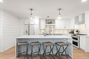 A modern kitchen with white cabinetry, a central island with stools, pendant lighting, and a stainless steel range hood. - Seaside Retreat - 3BR/3BA Gulf-Front Home - Private Pool & Beach Walkover - Sleeps 10 (Santa Rosa Beach)