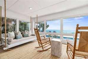 A beachside room with a swing chair, a wooden table, and a view of the ocean. - Seaside Retreat - 3BR/3BA Gulf-Front Home - Private Pool & Beach Walkover - Sleeps 10 (Santa Rosa Beach)