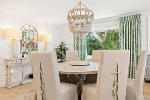 A dining area with a round table, four chairs, a chandelier, and a window with curtains. - Seaside Retreat - 3BR/3BA Gulf-Front Home - Private Pool & Beach Walkover - Sleeps 10 (Santa Rosa Beach)