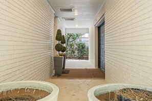 A corridor with white brick walls, a door at the end, and two planters with dried plants. - Seaside Retreat - 3BR/3BA Gulf-Front Home - Private Pool & Beach Walkover - Sleeps 10 (Santa Rosa Beach)