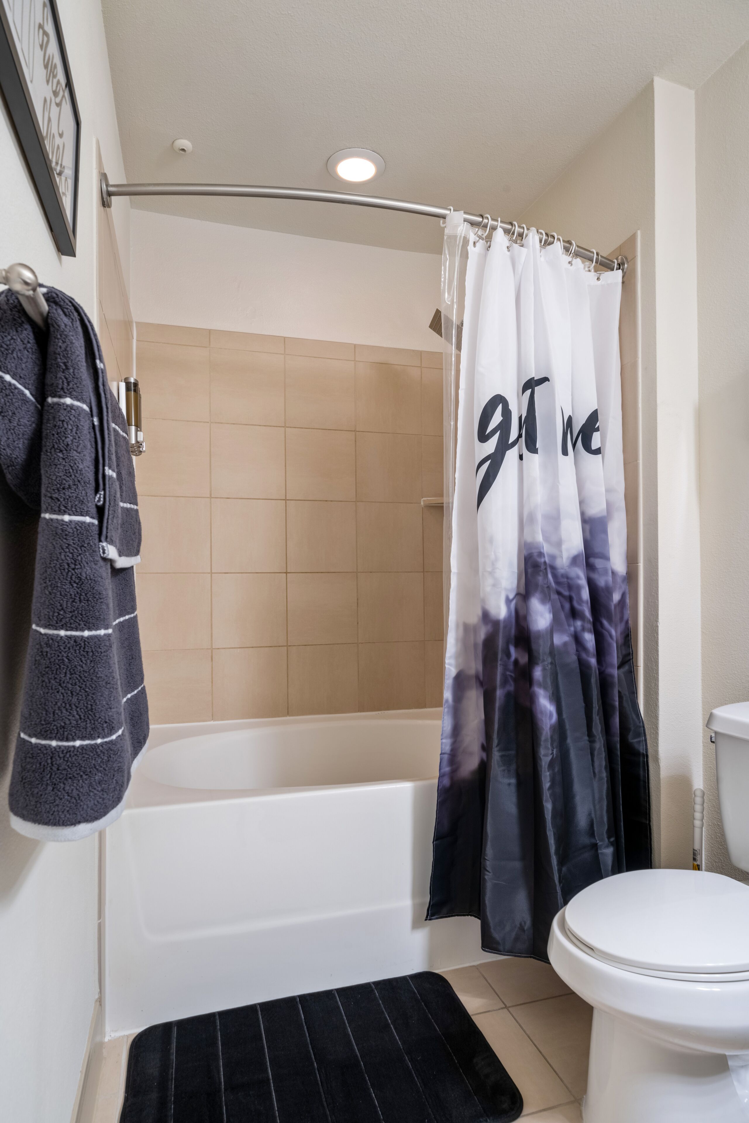 Een badkamer met een bad, een toilet en een douchegordijn met de tekst 'Get Me'.