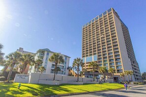 A high-rise hotel with multiple floors, a central courtyard with palm trees, and a sign indicating the location as Ocean Forest Plaza.