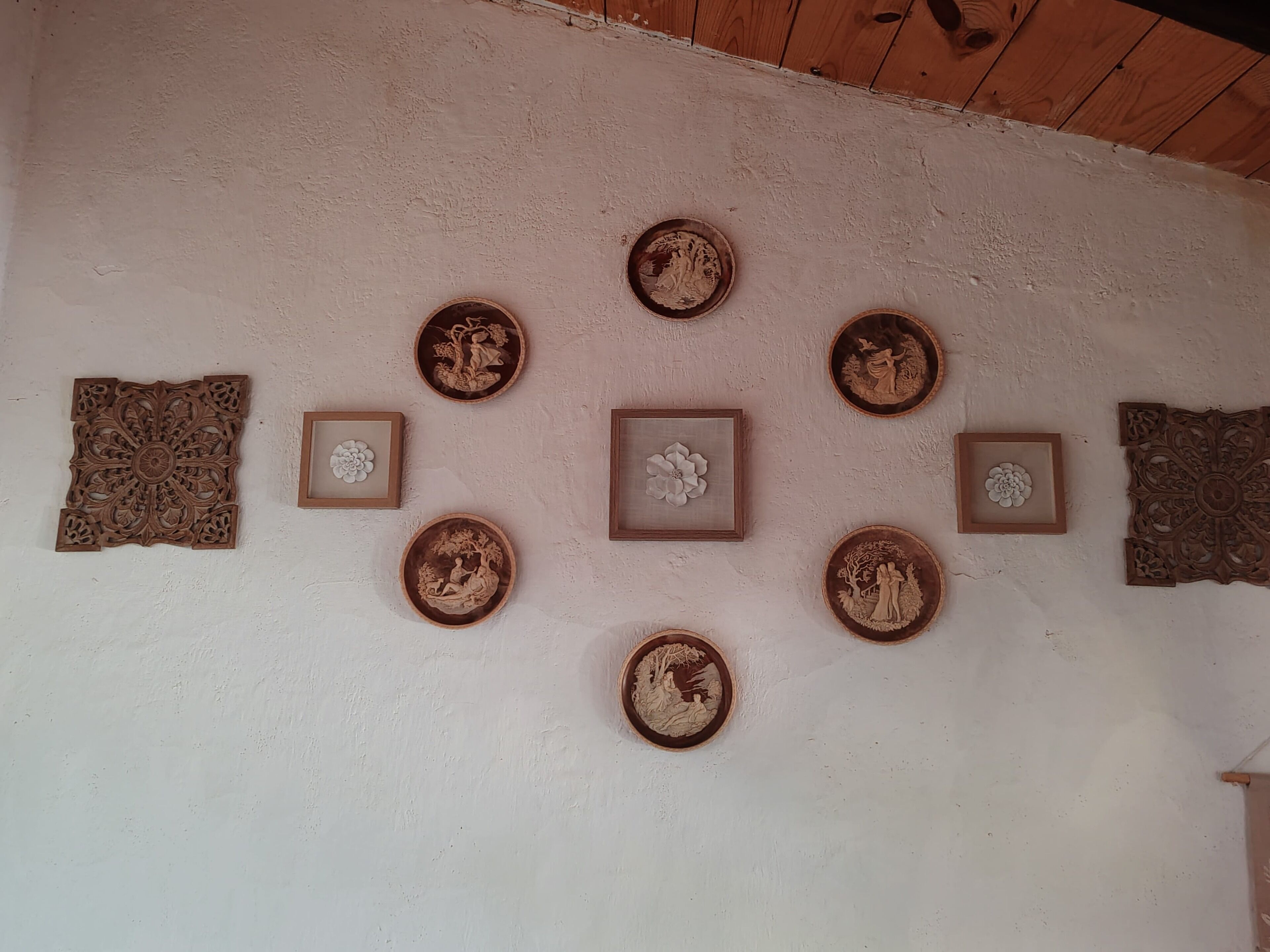 A wall with various decorative items including framed artwork and carved wooden pieces.