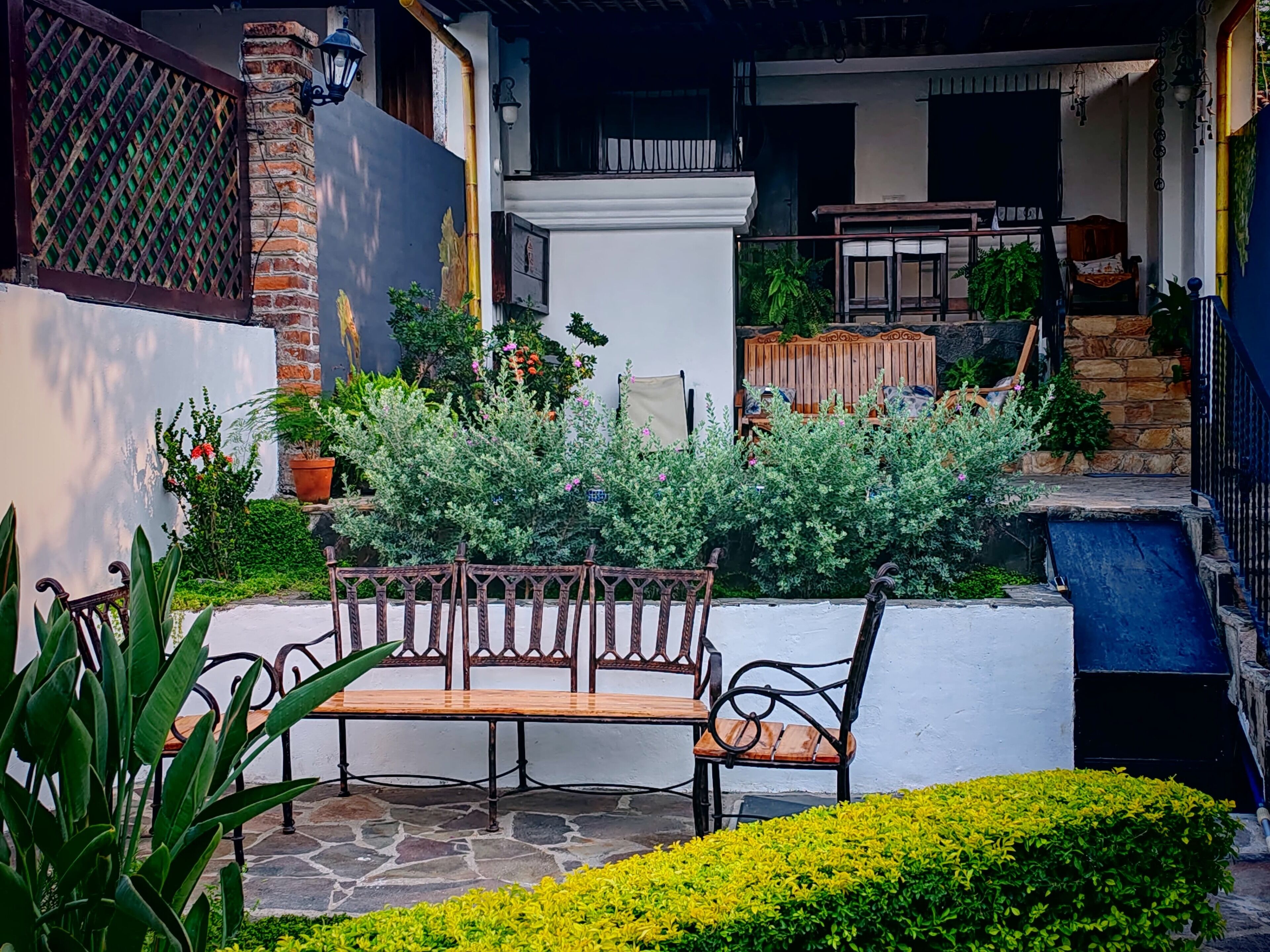 A courtyard with a wooden bench, potted plants, and a stone pathway.