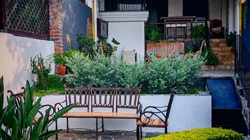 A courtyard with a wooden bench, potted plants, and a stone pathway.