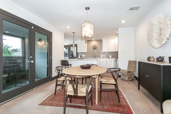 A modern kitchen with a round dining table, chairs, and a chandelier.