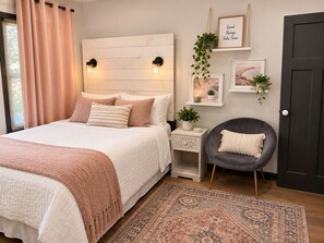 A bedroom with a bed, bedside tables, a chair, a rug, and wall decorations.