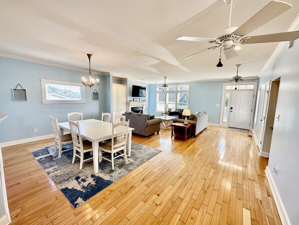 A spacious living area with a dining table, chairs, a sofa, and a ceiling fan.