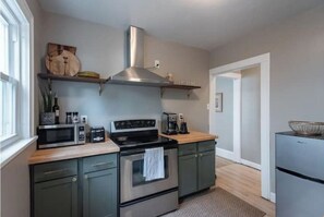 Compact kitchen area with a range hood, microwave, gas stove, and refrigerator.