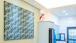 A dining area with a black table, white upholstered chairs, a large floral artwork on the wall, and a modern chandelier. - man man (Wujie)