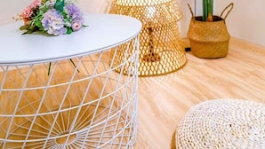 A modern living room with a round white table, a potted plant, a woven lamp, and a TV mounted on the wall. - man man (Wujie)