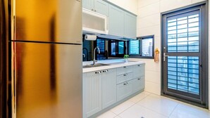A modern kitchen with grey cabinets, a stainless steel refrigerator, and a window with a view of the outside. - man man (Wujie)
