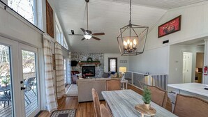 A spacious living area with a fireplace, wooden flooring, and a dining table with benches. - Sky Valley Creekside Getaway! Hike-Swim-Golf! (Sky Valley)