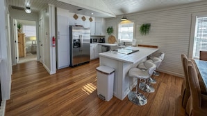 A modern kitchen with a central island, stainless steel appliances, and bar stools. - Sky Valley Creekside Getaway! Hike-Swim-Golf! (Sky Valley)