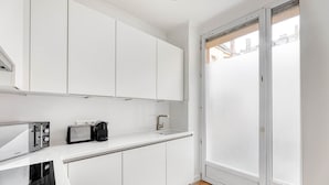 Eine moderne Küche mit weißen Schränken, einem Toaster, einem Wasserkocher und einer Mikrowelle.