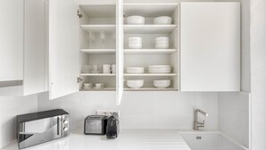 Eine moderne Küche mit weißen Schränken, einer eingebauten Mikrowelle, einem Toaster und einem Spülbecken.