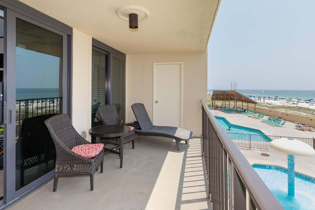 Un balcon avec une piscine, des chaises longues et une vue sur la plage.