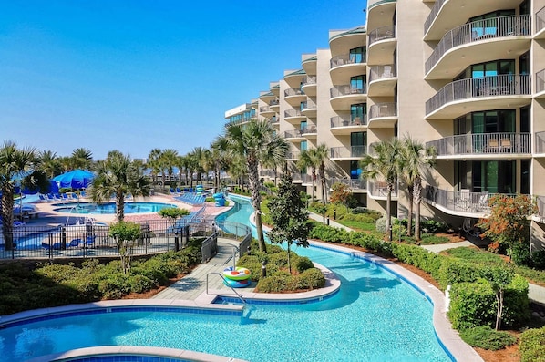 Un complexe hôtelier doté d’une piscine, de palmiers et d’un immeuble à plusieurs étages avec des balcons.