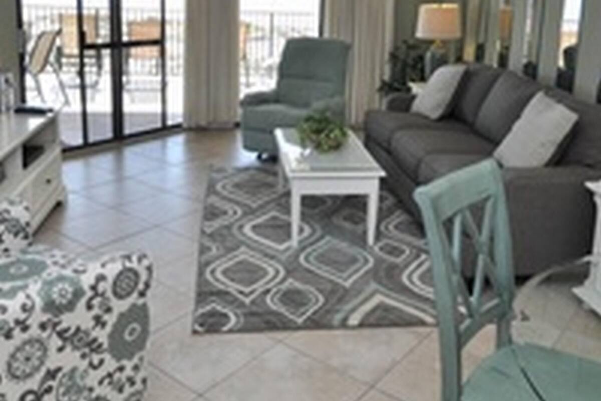 Una sala de estar con sofá, sillón, mesa de centro y alfombra estampada.