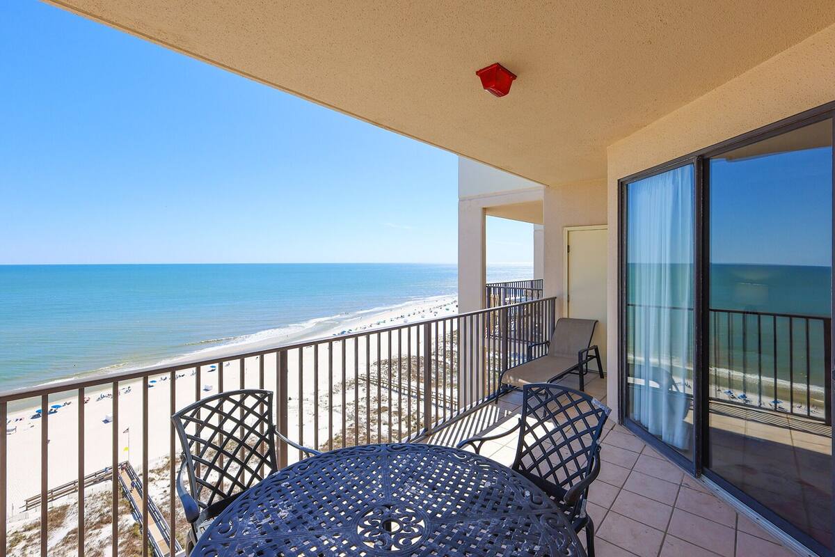 Un balcón con mesa y sillas con vista a la playa.