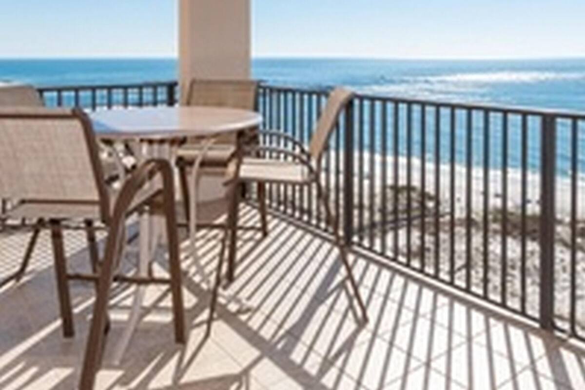 Un espacio exterior cubierto con una mesa y sillas, con vistas a una playa.