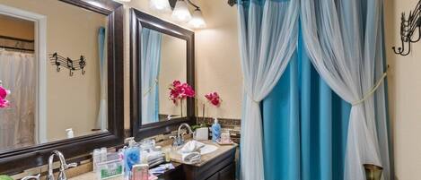 Un baño con un espejo grande, dos lavamanos, un tocador y una cortina de ducha.