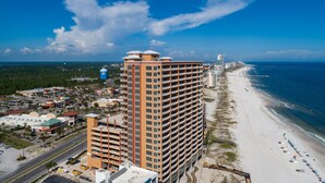 Un hotel moderno de gran altura con varias plantas, una playa y una torre de agua al fondo.