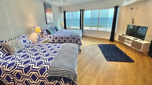 Une chambre d’hôtel moderne avec deux lits, une télévision et une grande fenêtre donnant sur la mer.