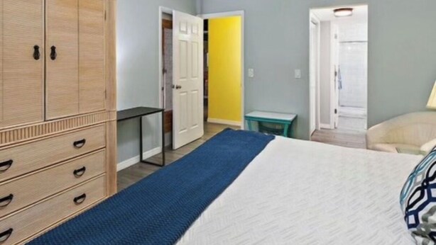 A bedroom with a bed, a wardrobe, a ceiling fan, and a door leading to another room. - Singer Island pool home (West Palm Beach)