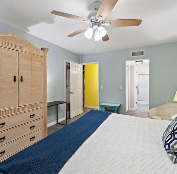 A bedroom with a bed, a wardrobe, a ceiling fan, and a door leading to another room. - Singer Island pool home (West Palm Beach)