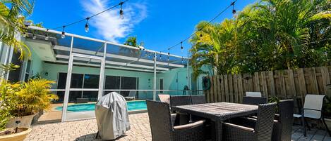 An outdoor patio with a pool, covered seating, and string lights.