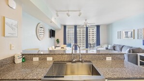 Una cocina moderna con encimeras de granito, un fregadero de acero inoxidable y un ventilador de techo.